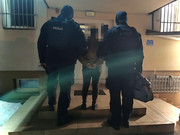policjanci prowadzą zatrzymaną kobietę