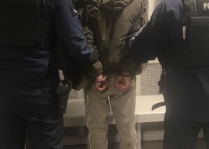 zatrzymany z kajdankami na rękach trzymanych z tyłu