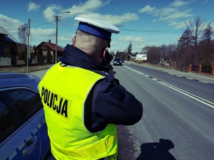 policjant stojący tyłem i mierzący prędkość