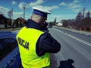 policjant stojący tyłem i mierzący prędkość