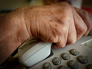 dłoń osoby starszej trzymająca słuchawkę telefonu